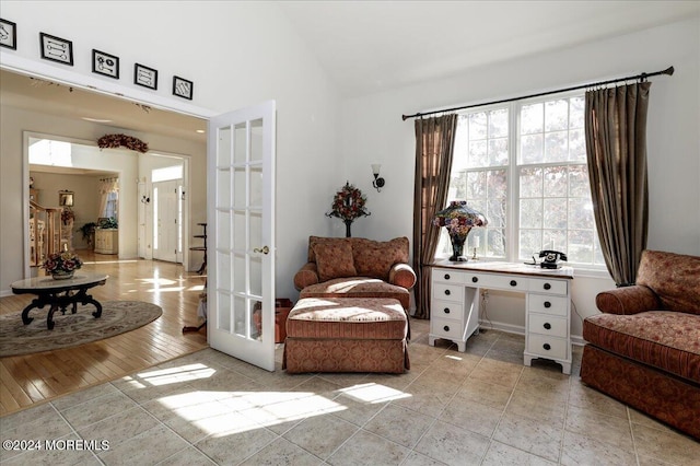 living area featuring french doors, light hardwood / wood-style flooring, and vaulted ceiling