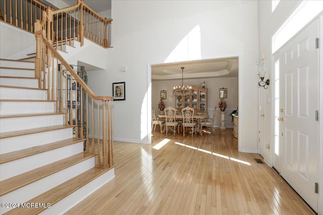 entrance foyer featuring an inviting chandelier, hardwood / wood-style floors, crown molding, and a towering ceiling