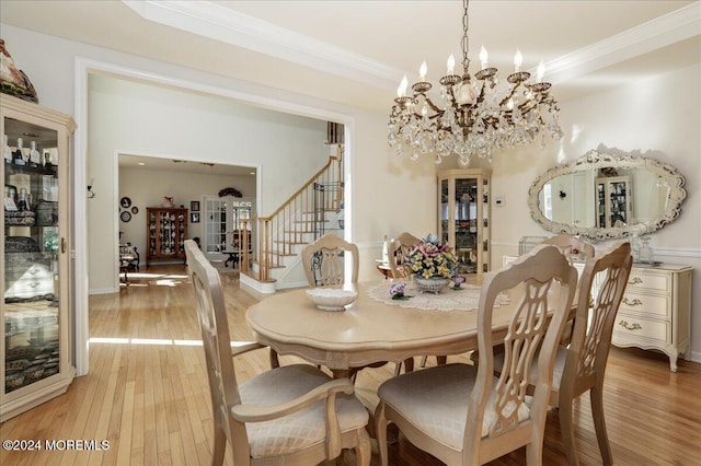 dining space featuring wood-type flooring, ornamental molding, and a notable chandelier