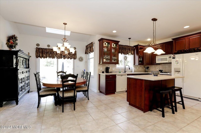 kitchen with a chandelier, decorative light fixtures, a center island, and white appliances