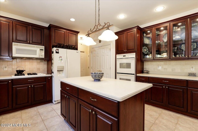 kitchen featuring decorative backsplash, hanging light fixtures, light tile patterned flooring, a kitchen island, and white appliances