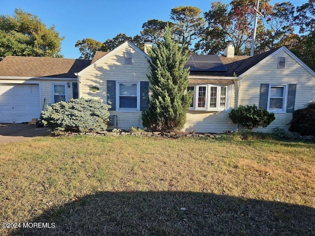 ranch-style home with a front yard, solar panels, and a garage