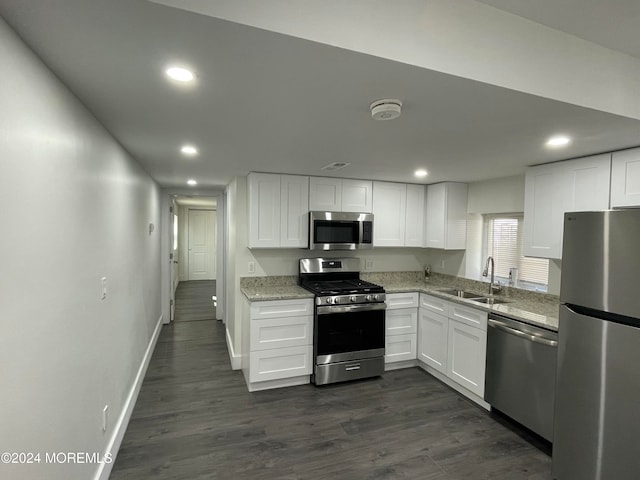 kitchen with light stone counters, dark hardwood / wood-style flooring, appliances with stainless steel finishes, white cabinetry, and sink