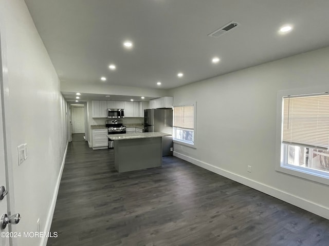 kitchen featuring a kitchen island, white cabinetry, stainless steel appliances, and a healthy amount of sunlight