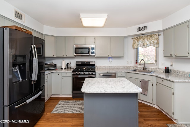 kitchen featuring gray cabinetry, appliances with stainless steel finishes, sink, a kitchen island, and hardwood / wood-style floors