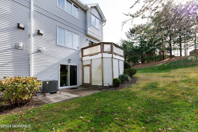 rear view of house with cooling unit and a yard