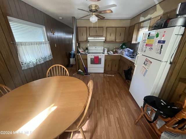 kitchen featuring white appliances, ceiling fan, wood walls, and light hardwood / wood-style flooring