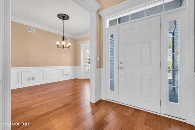 foyer entrance featuring ornamental molding, a chandelier, and wood-type flooring