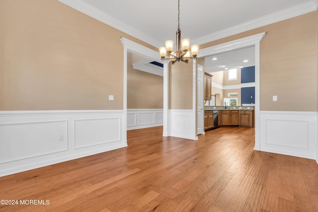 unfurnished dining area featuring an inviting chandelier, ornamental molding, and light wood-type flooring