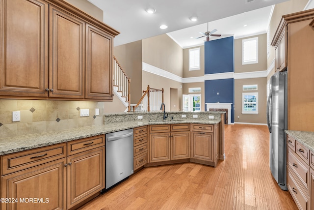 kitchen featuring kitchen peninsula, a high ceiling, stainless steel appliances, and light wood-type flooring