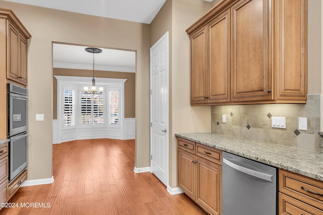 kitchen featuring stainless steel appliances, ornamental molding, light stone countertops, light wood-type flooring, and a chandelier