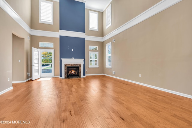 unfurnished living room with a towering ceiling, light hardwood / wood-style flooring, and plenty of natural light