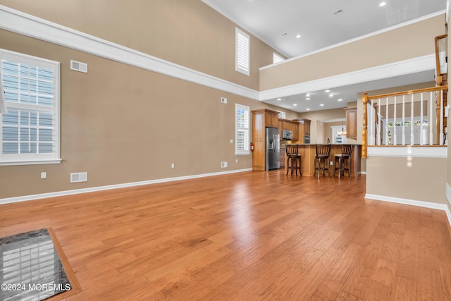 unfurnished living room with a towering ceiling and light wood-type flooring