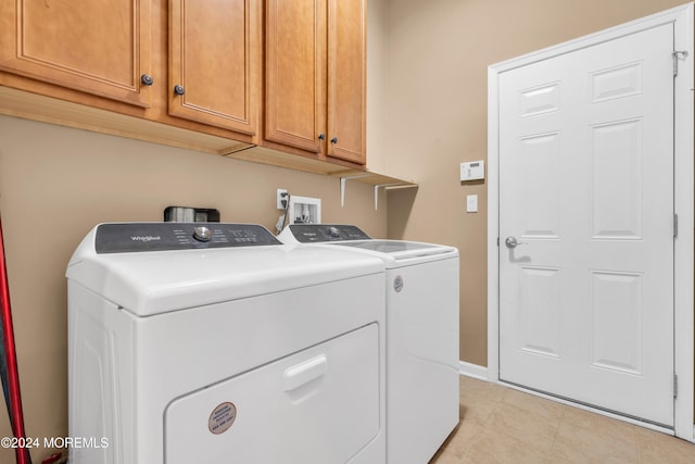 laundry area featuring light tile patterned floors, cabinets, and separate washer and dryer