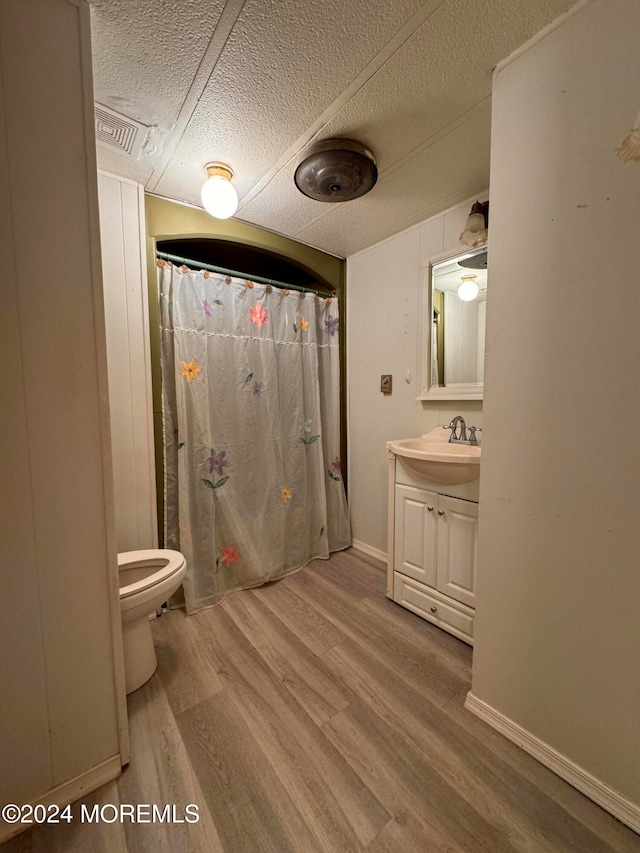 bathroom featuring vanity, a textured ceiling, hardwood / wood-style flooring, and walk in shower