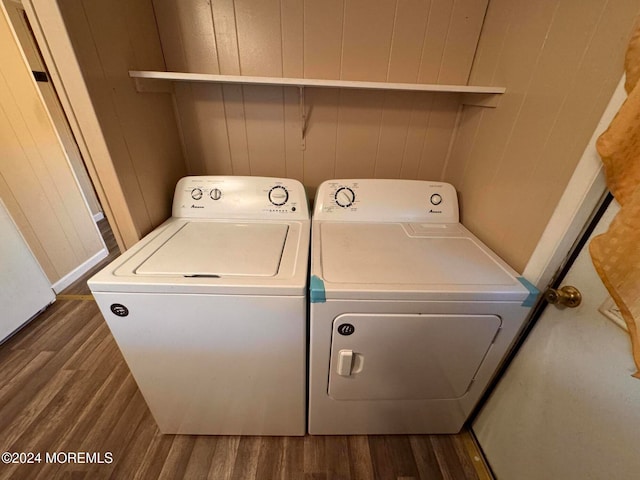 laundry room with wooden walls, dark wood-type flooring, and independent washer and dryer