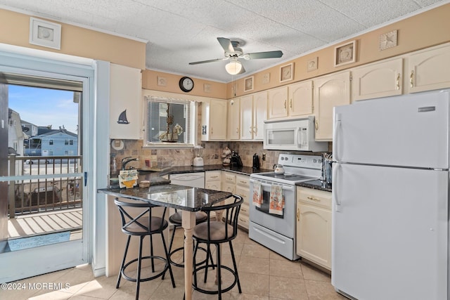 kitchen featuring light tile patterned flooring, backsplash, a kitchen breakfast bar, white appliances, and ceiling fan