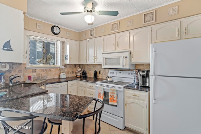 kitchen featuring light tile patterned flooring, sink, ceiling fan, a breakfast bar area, and white appliances