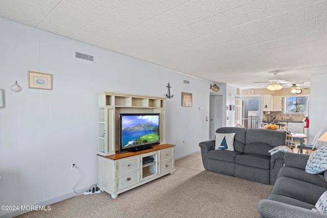 carpeted living room with ceiling fan