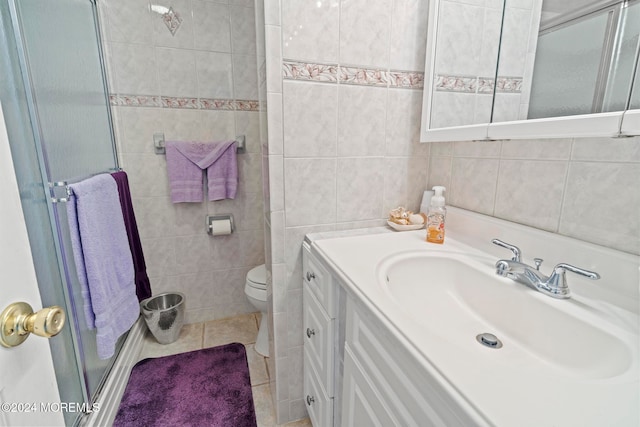 bathroom with vanity, a shower with door, tile patterned flooring, and tile walls