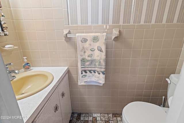 bathroom with vanity, toilet, and tile walls