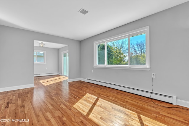 unfurnished room featuring light hardwood / wood-style flooring, a healthy amount of sunlight, and baseboard heating