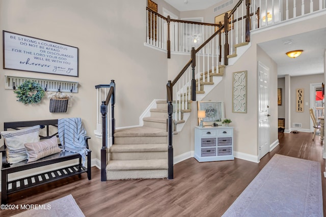 staircase with hardwood / wood-style flooring and a towering ceiling