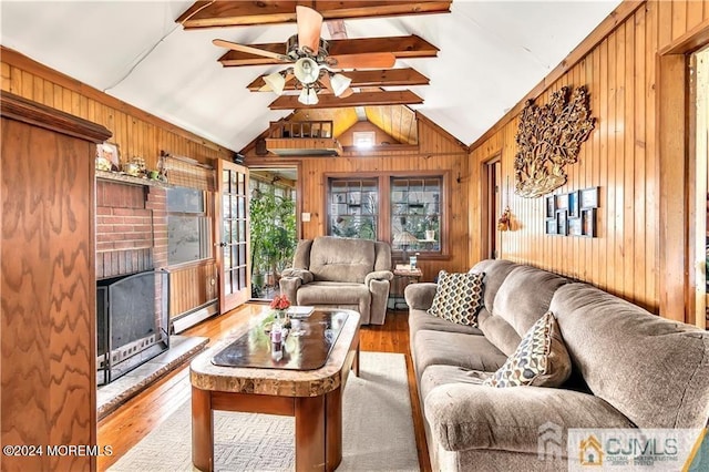 living room with wood walls, hardwood / wood-style floors, lofted ceiling with beams, and a baseboard radiator