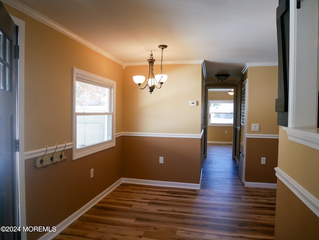 unfurnished dining area with dark wood-type flooring, ornamental molding, and a chandelier