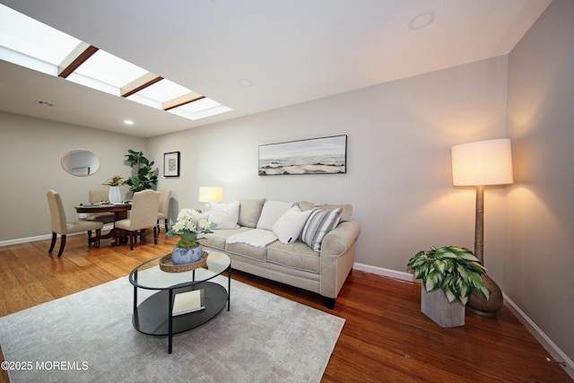 living room with dark wood-type flooring and a skylight