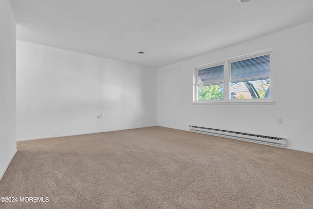 carpeted spare room featuring a baseboard heating unit