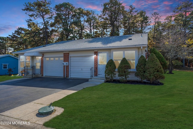 view of front of home with a garage and a lawn