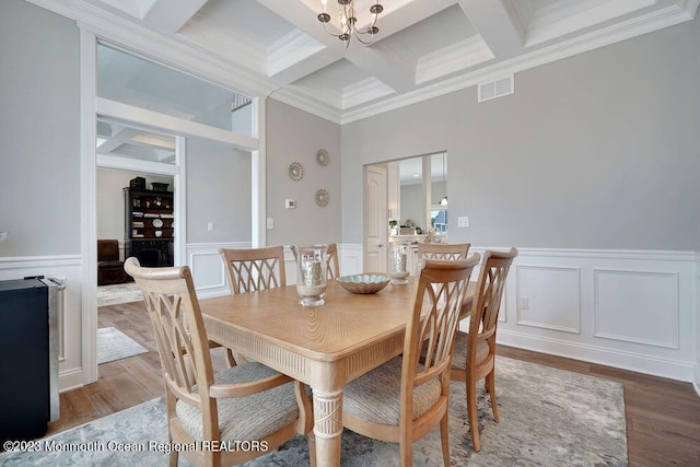 dining room featuring beamed ceiling, wood-type flooring, coffered ceiling, crown molding, and an inviting chandelier