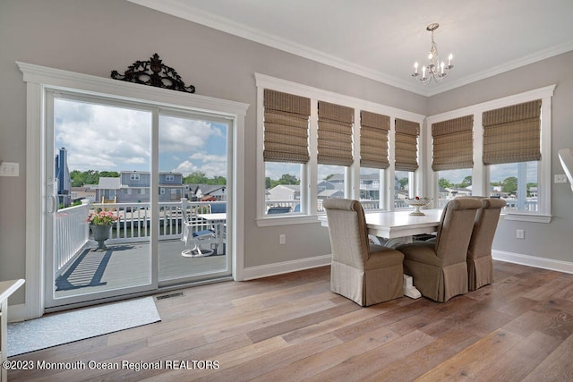 dining area featuring ornamental molding, a notable chandelier, and light wood-type flooring