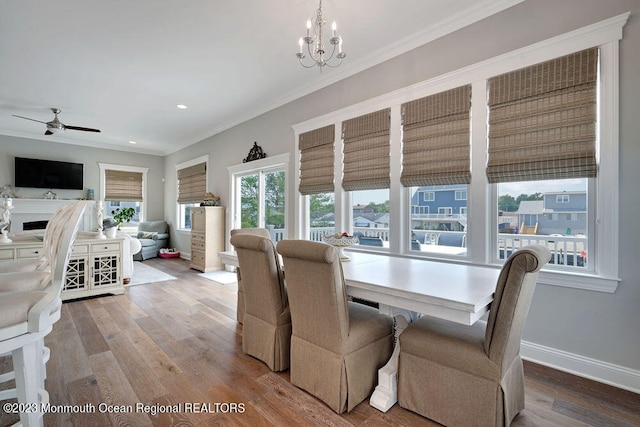 dining area featuring crown molding, hardwood / wood-style flooring, and ceiling fan with notable chandelier