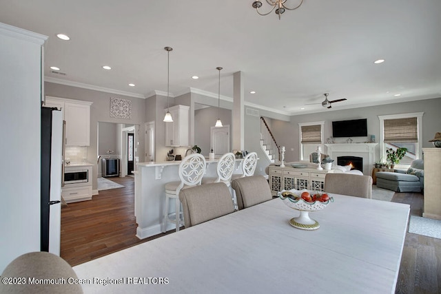 dining area with crown molding, dark wood-type flooring, and ceiling fan