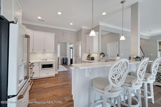 kitchen with built in microwave, white cabinetry, dark hardwood / wood-style flooring, hanging light fixtures, and white fridge with ice dispenser