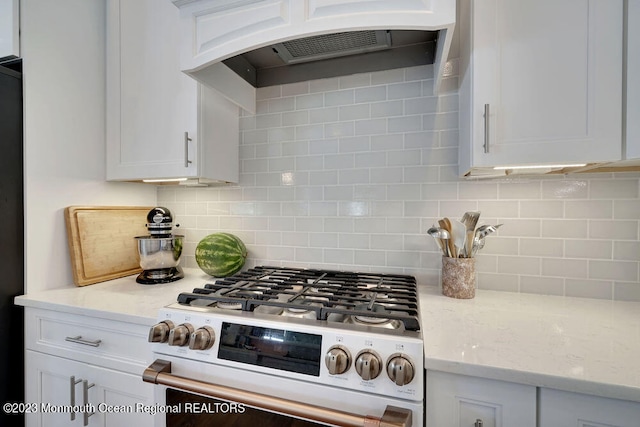 kitchen with light stone countertops, white gas stove, custom range hood, and white cabinets