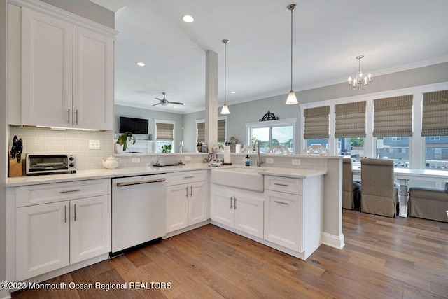 kitchen with sink, white cabinetry, hanging light fixtures, kitchen peninsula, and dishwasher