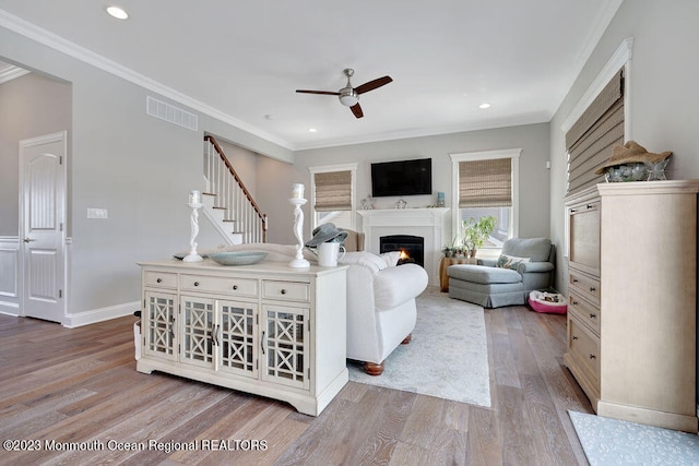 living room with crown molding, ceiling fan, and light hardwood / wood-style flooring