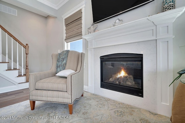 sitting room with a premium fireplace, ornamental molding, and light hardwood / wood-style floors