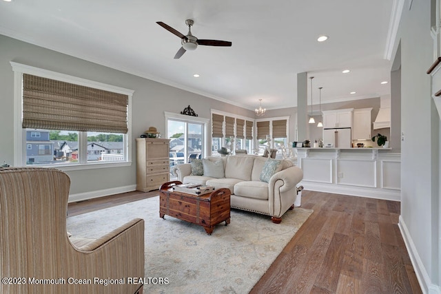 living room with ornamental molding, ceiling fan with notable chandelier, and light hardwood / wood-style floors