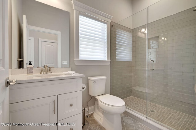 bathroom with a shower with door, vanity, and toilet