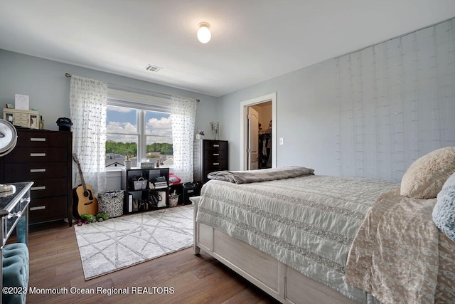 bedroom featuring wood-type flooring and a walk in closet