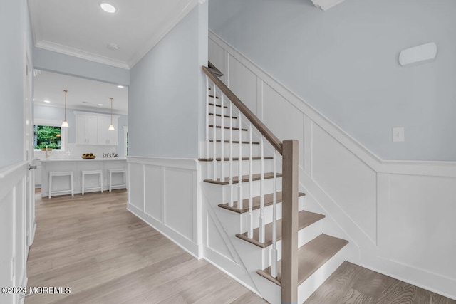 stairs featuring ornamental molding and wood-type flooring