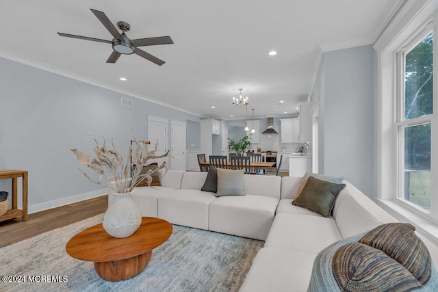 living room featuring crown molding, wood-type flooring, ceiling fan with notable chandelier, and a wealth of natural light