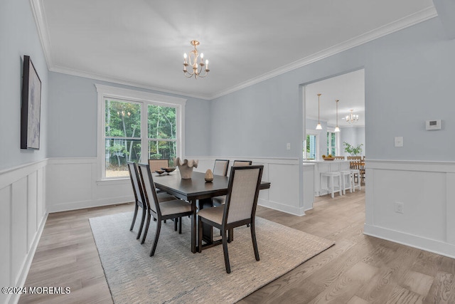 dining area with crown molding, light hardwood / wood-style flooring, and a notable chandelier