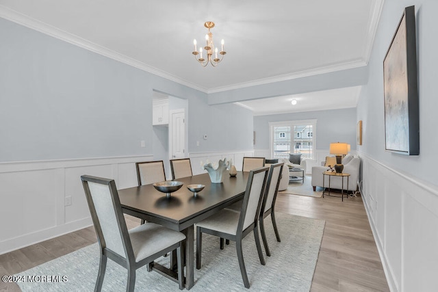 dining space with light hardwood / wood-style flooring, ornamental molding, and a chandelier