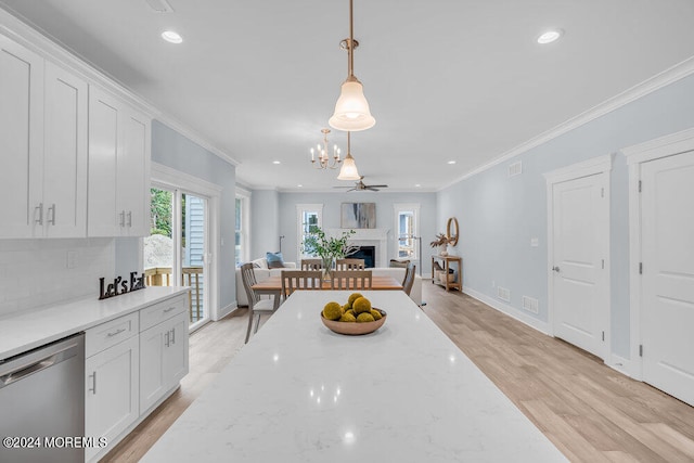 kitchen with light wood-type flooring, white cabinetry, decorative light fixtures, stainless steel dishwasher, and ornamental molding