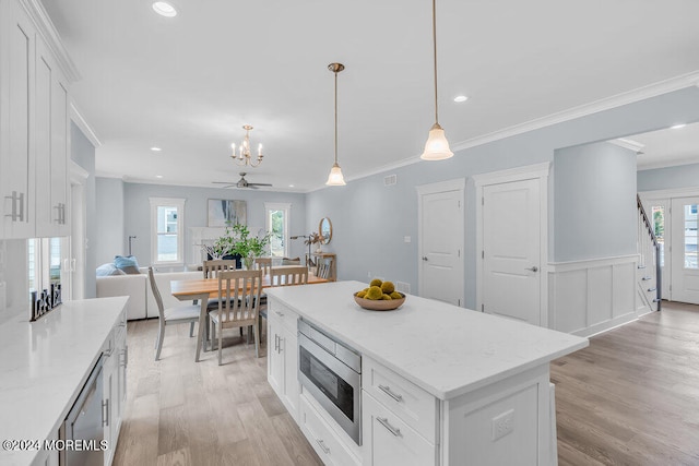 kitchen with a kitchen island, hanging light fixtures, white cabinetry, ceiling fan, and light hardwood / wood-style flooring